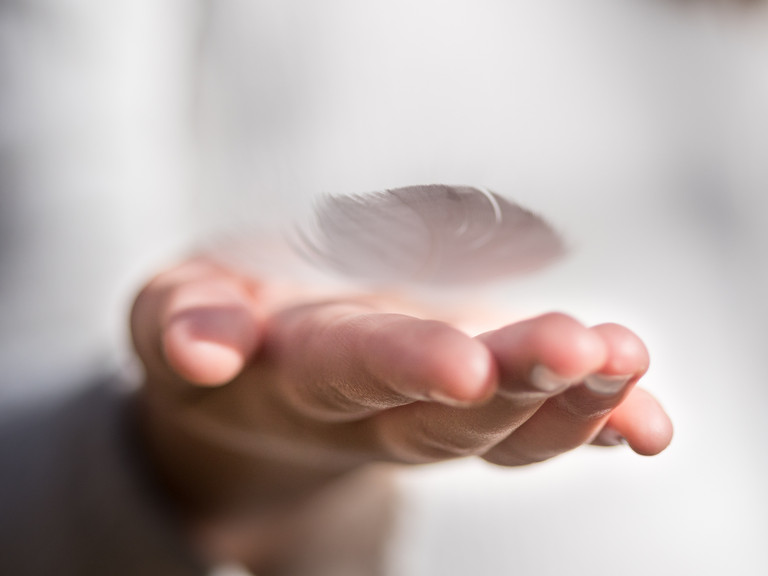 Eine flach ausgestreckte Hand mit einer Feder auf der Handinnenfläche zum Impuls für den Beginn der Fastenzeit in den Einrichtungen der Immanuel Albertinen Diakonie 